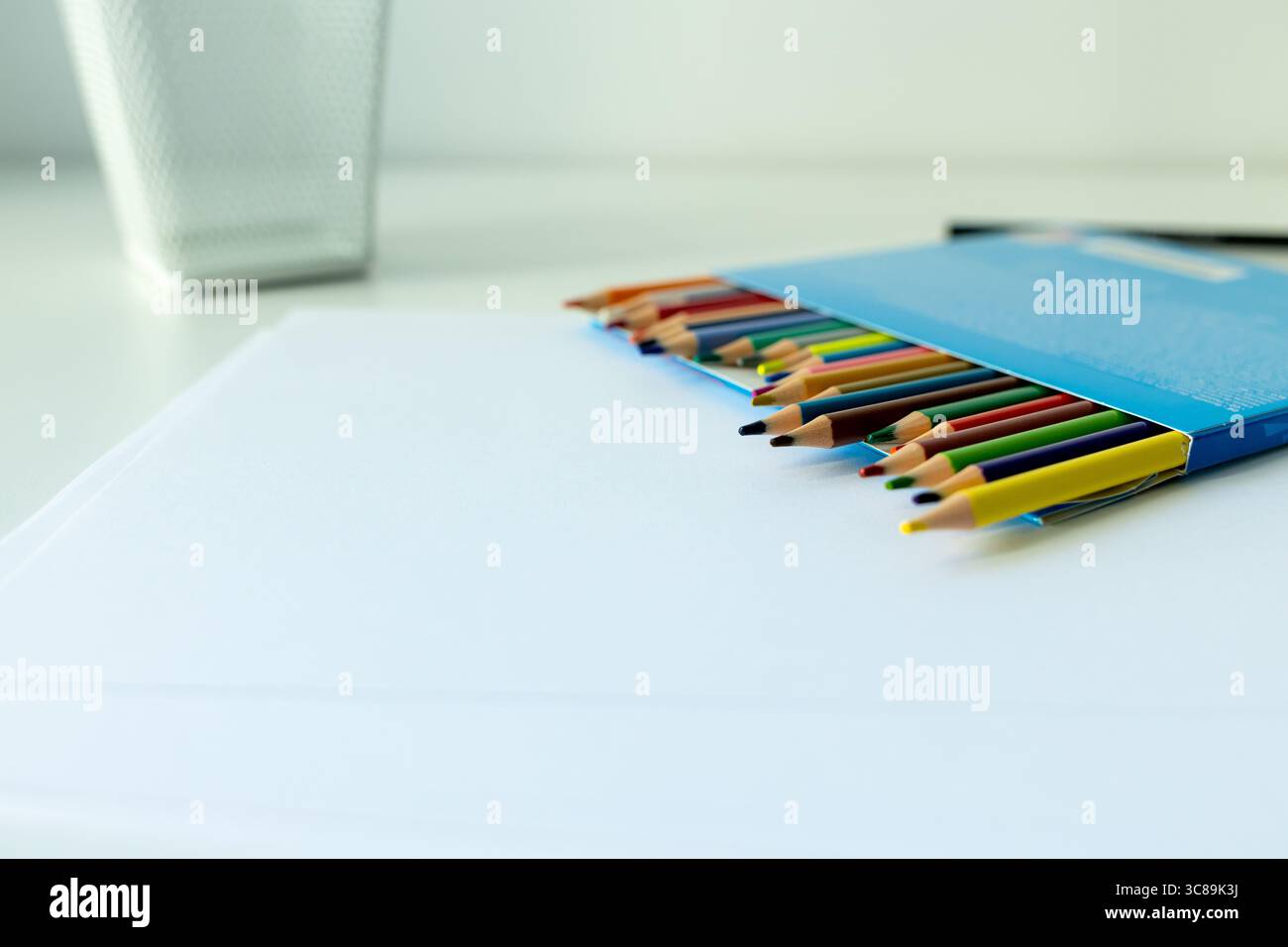 bureau blanc avec support avec crayons de couleur et carnet de croquis. fournitures scolaires sur la table magnifiquement éclairées par une lampe de bureau Banque D'Images