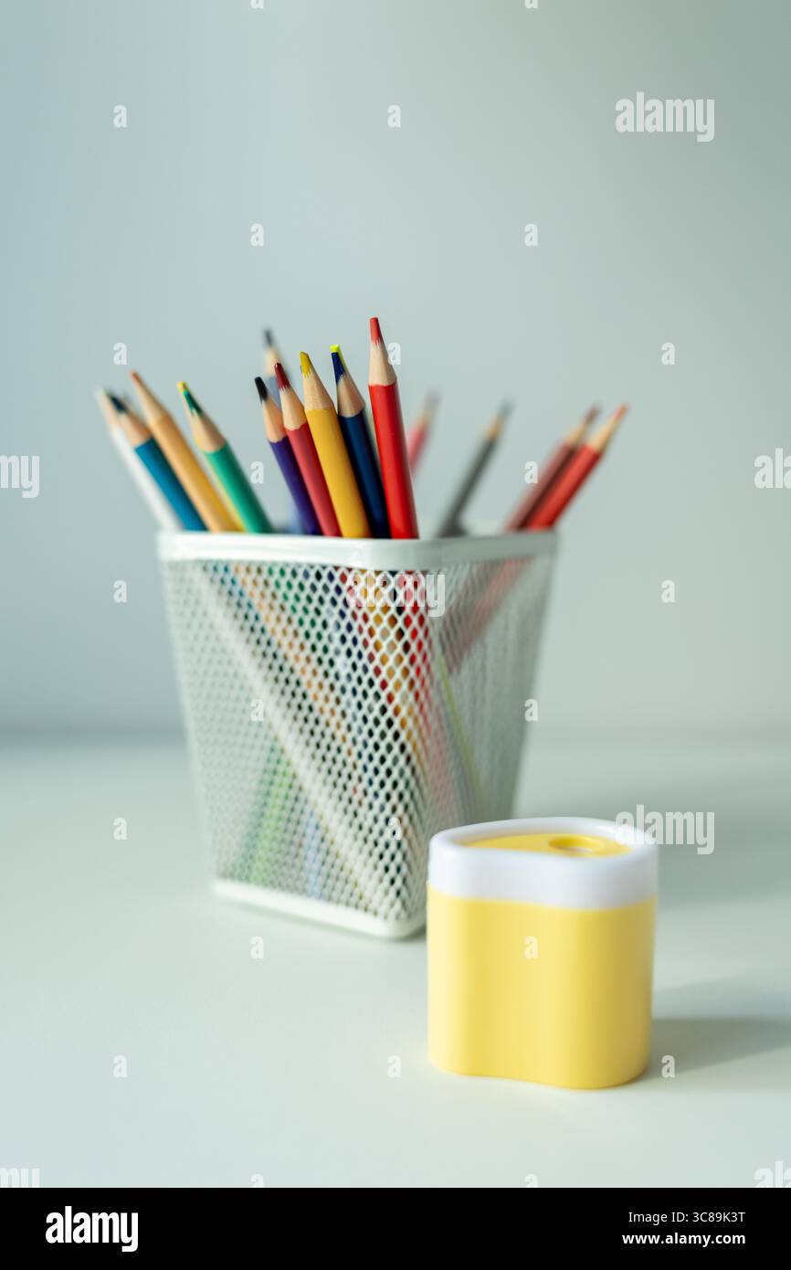 bureau blanc avec support avec crayons de couleur et carnet de croquis. fournitures scolaires sur la table magnifiquement éclairées par une lampe de bureau Banque D'Images