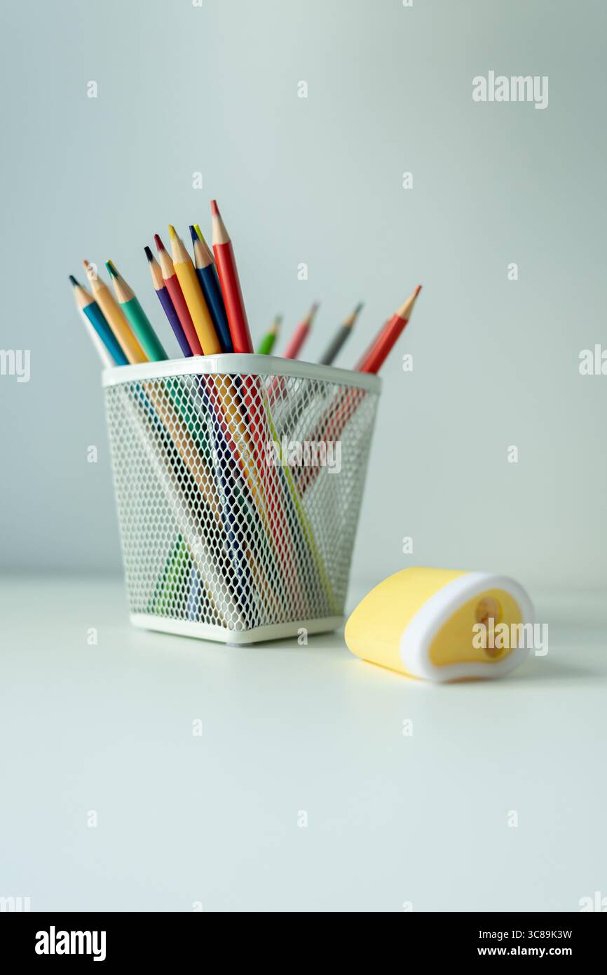 bureau blanc avec support avec crayons de couleur et carnet de croquis. fournitures scolaires sur la table magnifiquement éclairées par une lampe de bureau Banque D'Images