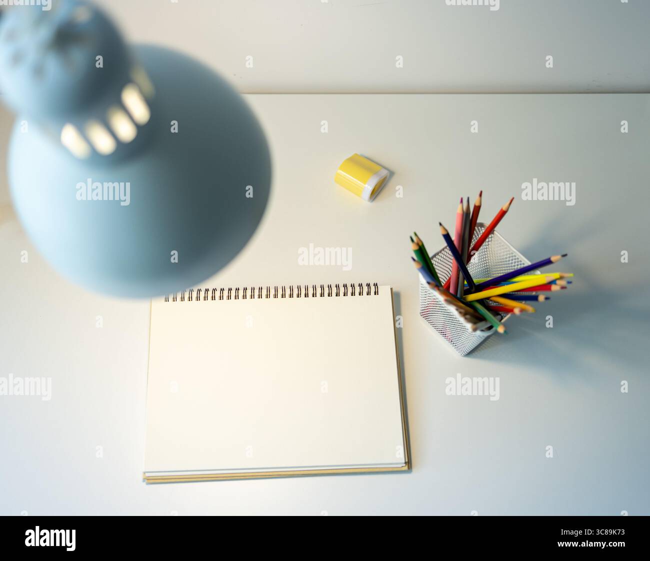 carnet de croquis illuminé par lampe et jeu de crayons de couleur sur table, dessin et passe-temps, concept de retour à l'école Banque D'Images