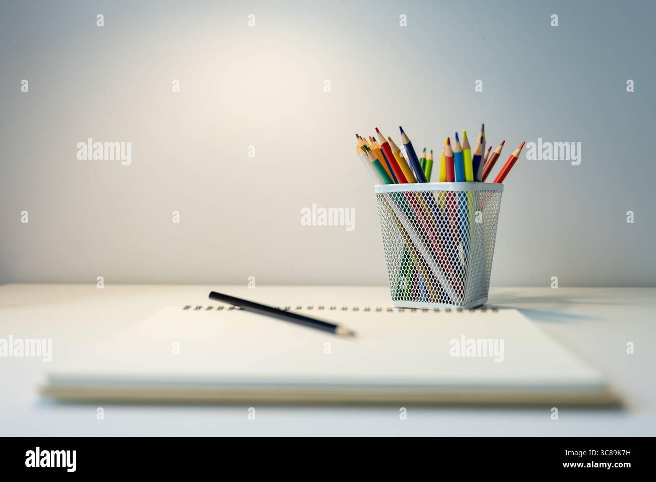 carnet de croquis illuminé par lampe et jeu de crayons de couleur sur table, dessin et passe-temps, concept de retour à l'école Banque D'Images