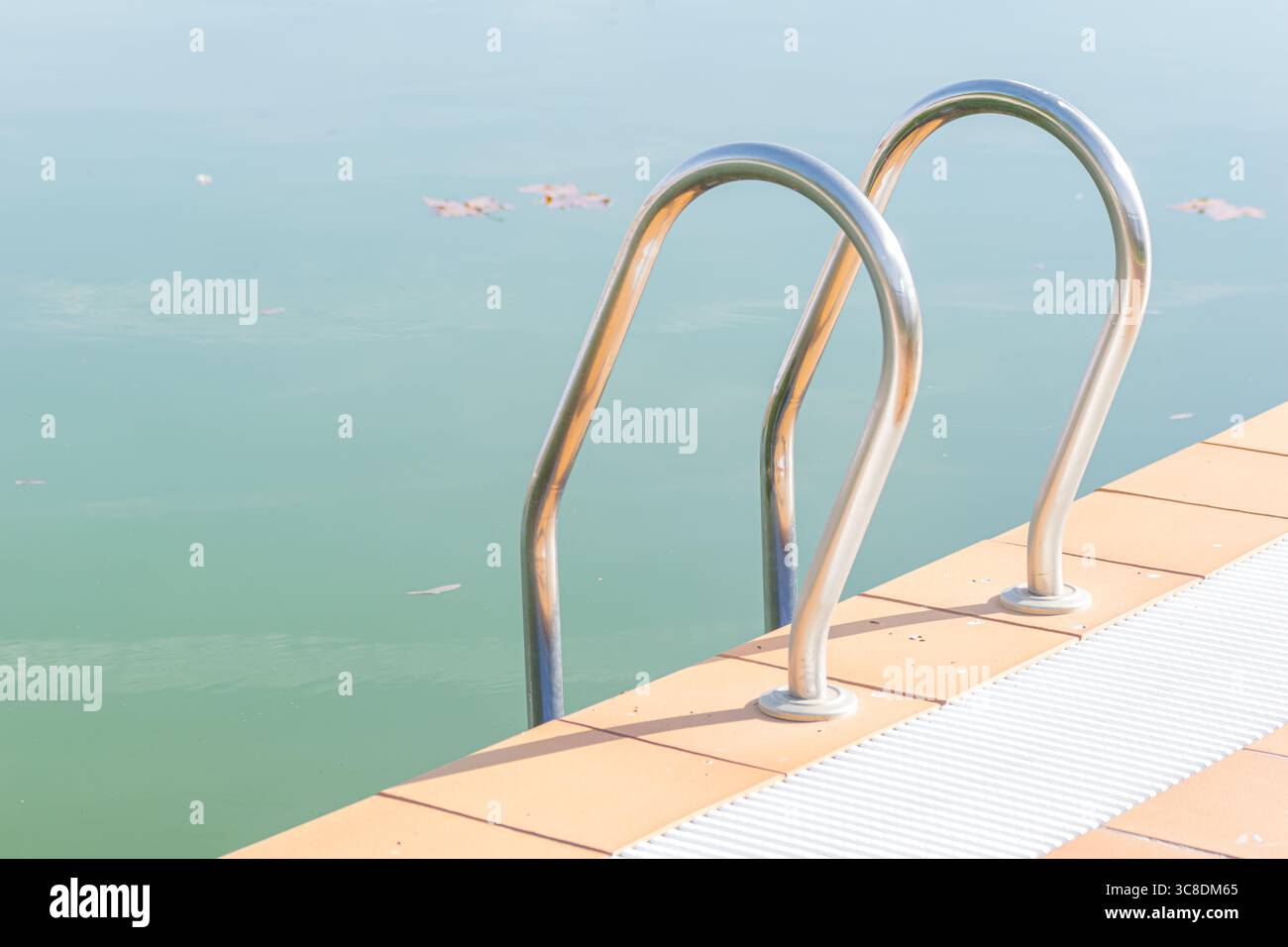 L'échelle en acier inoxydable d'une piscine par une journée ensoleillée. Banque D'Images