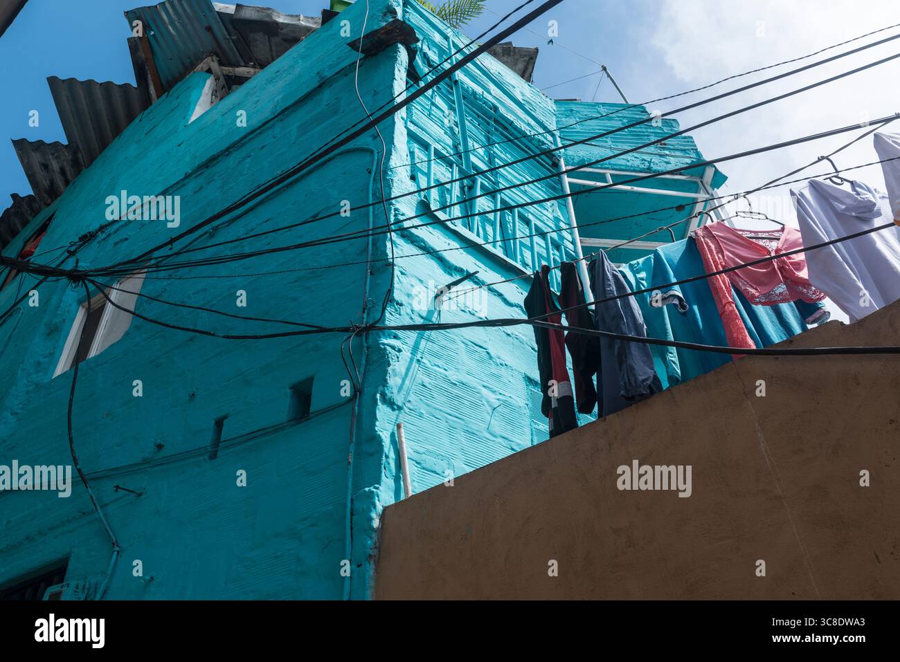 Vue vers le haut d'une maison peinte turquoise avec linge séchant dans le quartier pauvre de Medellin en Moravie, Colombie. Banque D'Images