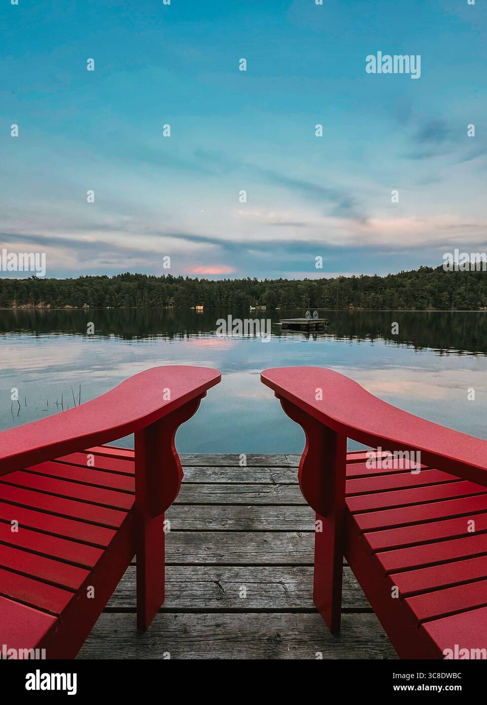 Bras rouges de chaises adirondack en bois sur quai avec vue sur le lac. Banque D'Images