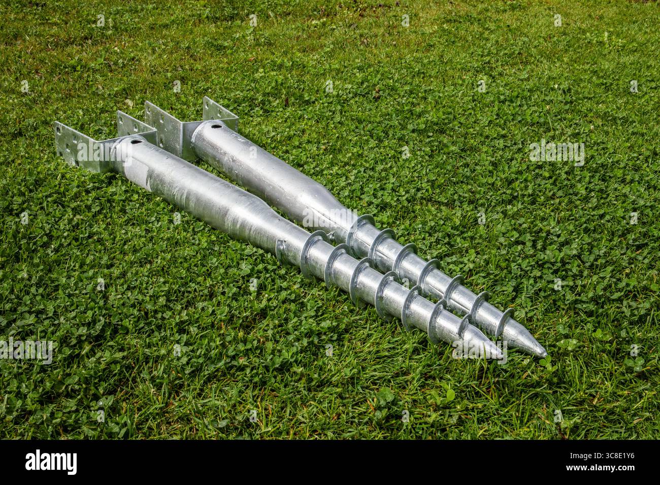 Vis de terre métalliques pour ancrage de fondation sur herbe verte. Banque D'Images Vis de terre métalliques pour ancrage de fondation sur herbe verte. Banque D'Images