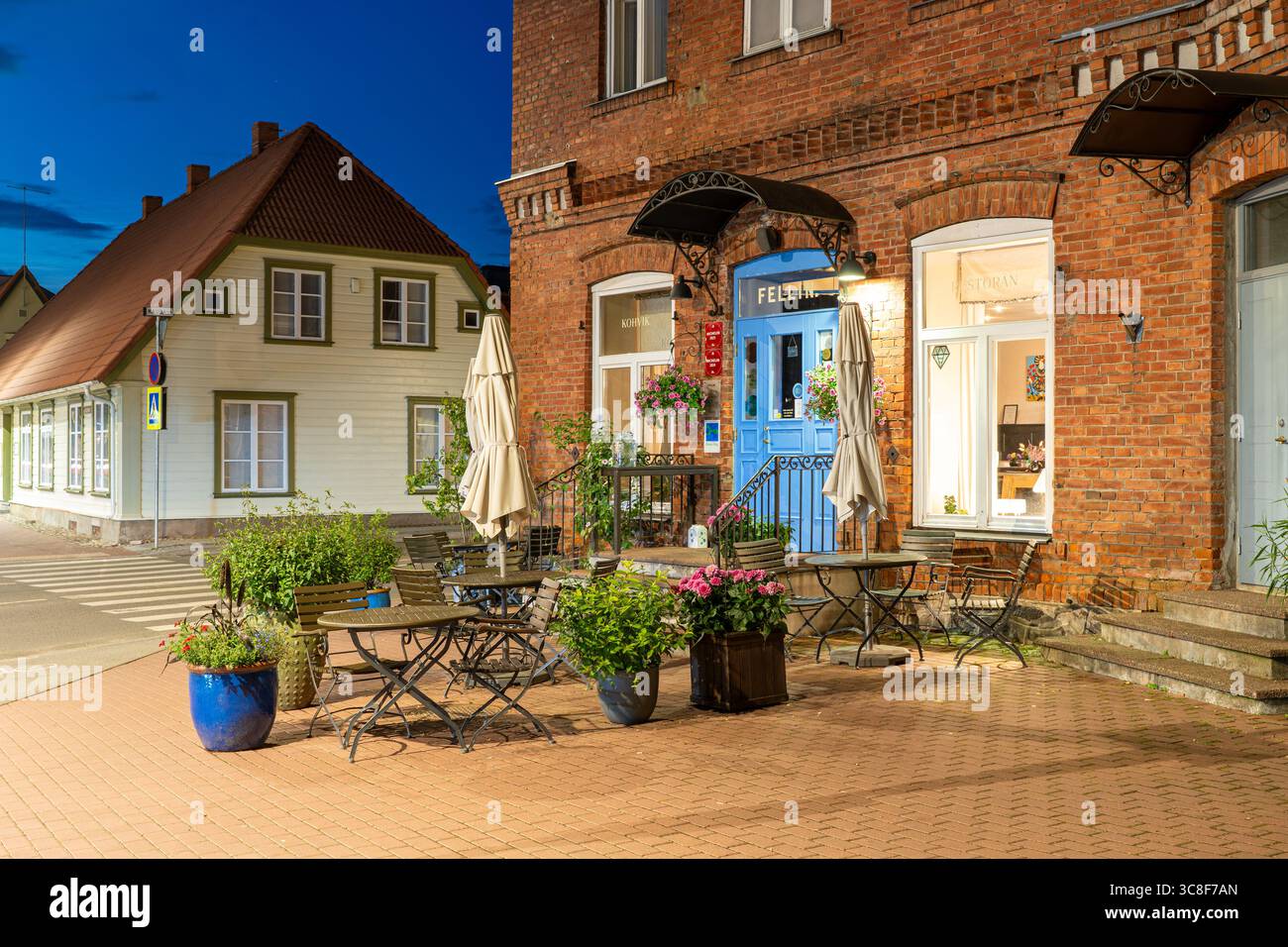 Restaurant Fellin terrasse extérieure la nuit avec porte bleue et bâtiment historique en briques dans la vieille ville de Viljandi, Estonie Banque D'Images