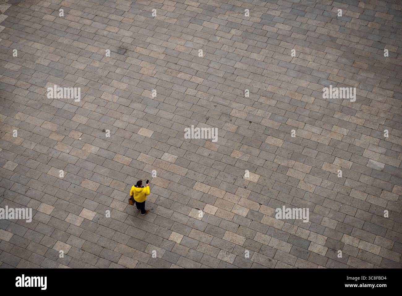 Personne en veste jaune marchant sur la place pavée de pierre, vue aérienne Banque D'Images