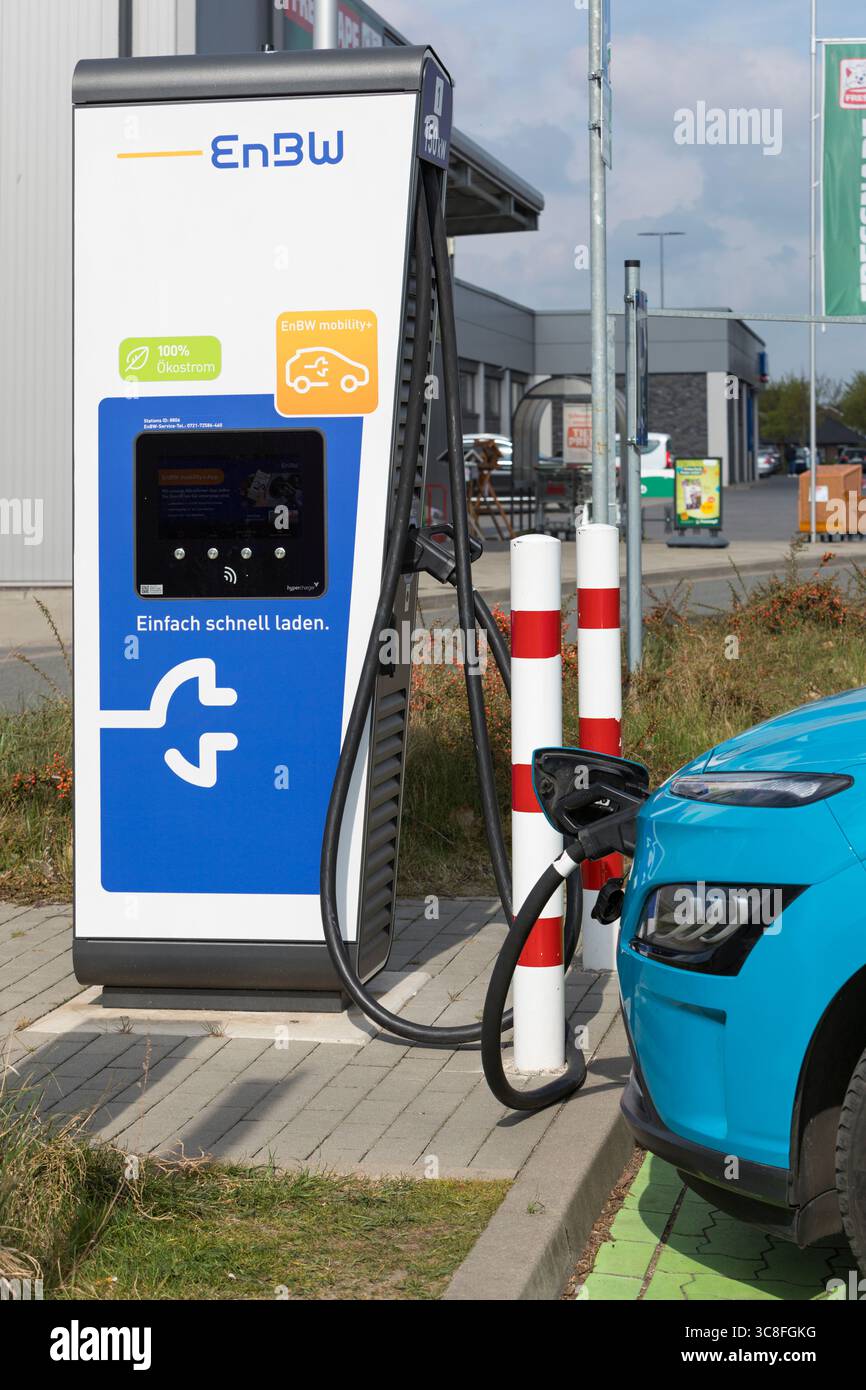 Stade, Allemagne – 16 avril 2025 : véhicule électrique branché à une borne de recharge rapide installée par la société d’énergie EnBW sur le parking d’un supermarché. Banque D'Images
