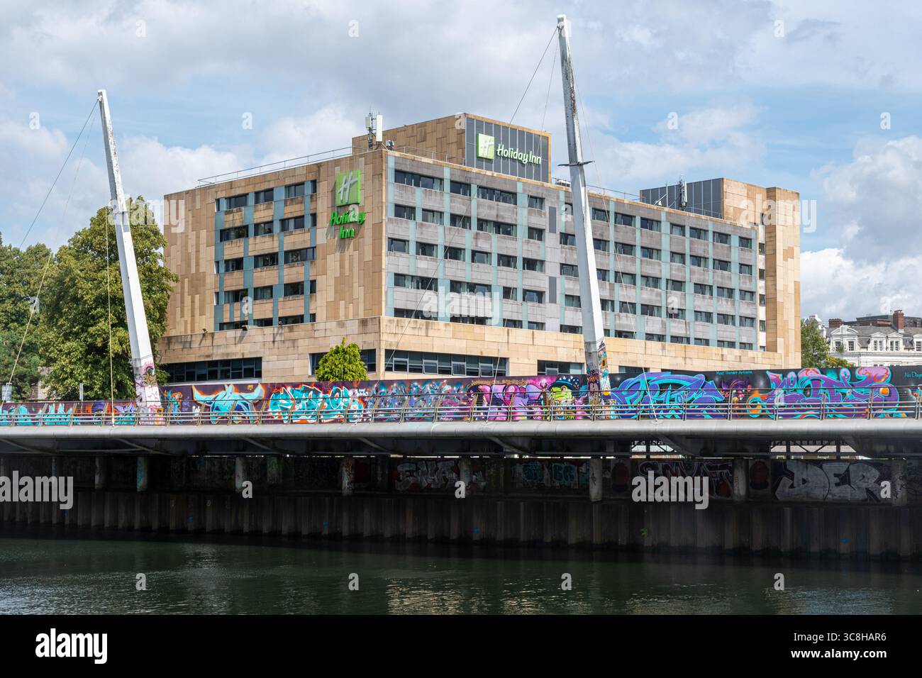 Holiday Inn, hébergement à l'hôtel à Cardiff, pays de Galles du Sud, Royaume-Uni, vue de l'autre côté de la rivière Taff jusqu'au Millennium Walkway avec un mur de graffitis coloré Banque D'Images