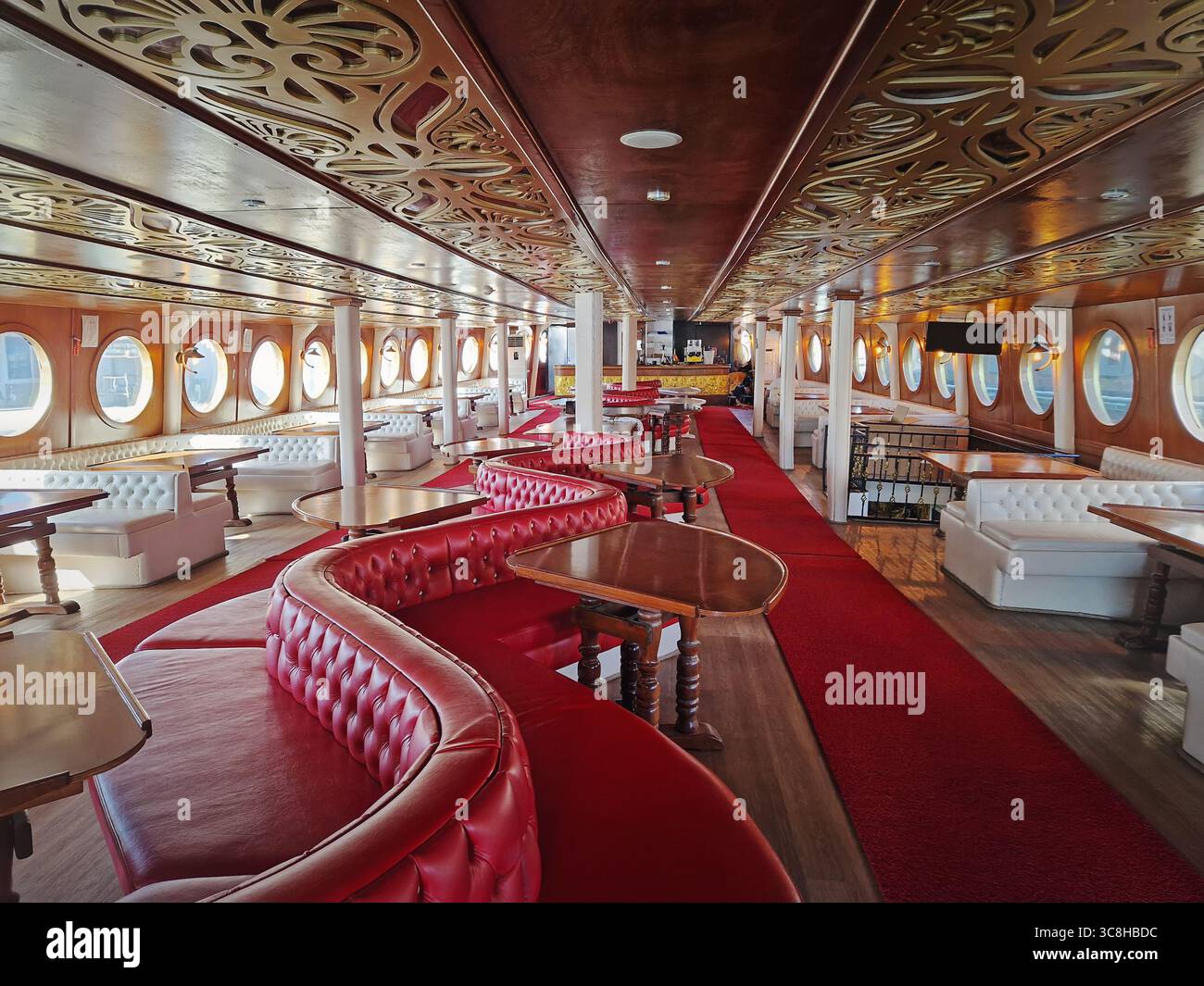 Intérieur luxueux du navire avec long hall, tapis rouges, canapés en cuir et tables en bois courbées. Motifs dorés ornés ornent le plafond, et circulaires Banque D'Images