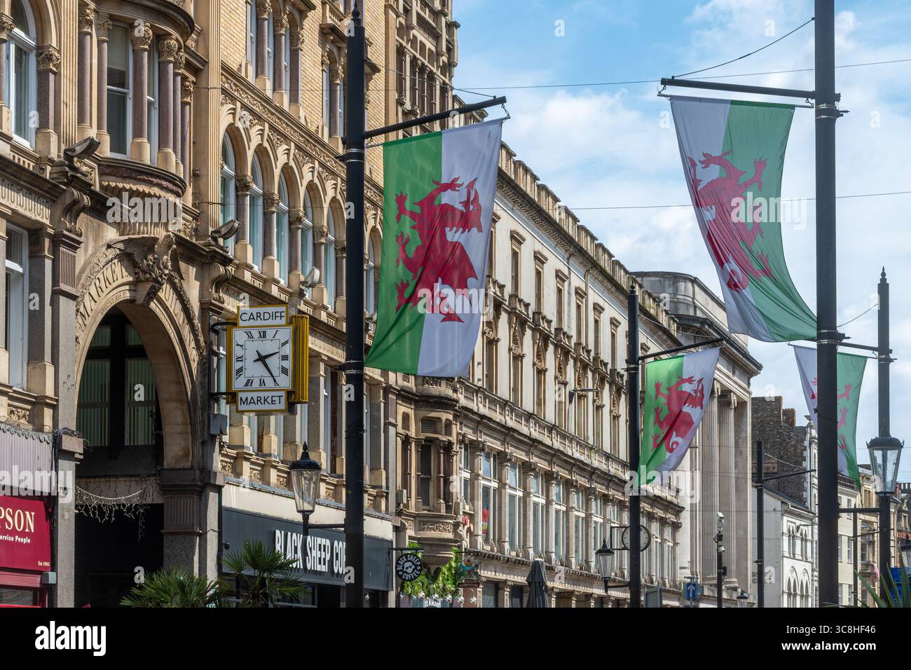 Drapeaux de dragon gallois le long de St Mary Street à Cardiff, capitale du pays de Galles, Royaume-Uni, avec l'entrée du marché de Cardiff Banque D'Images
