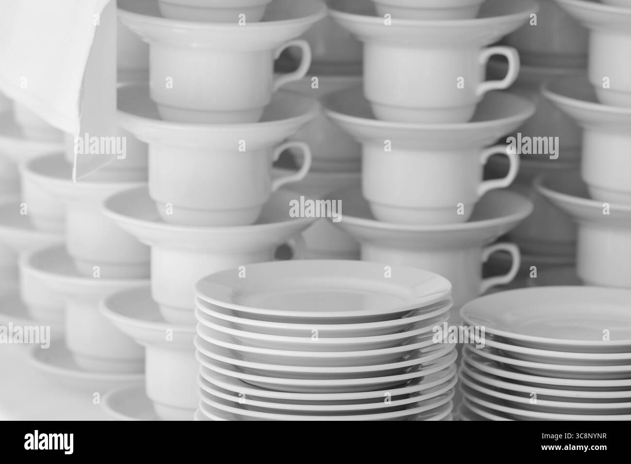 Assiettes blanches et tasses à thé soigneusement disposées empilées verticalement, présentant un look organisé et propre, adapté à la restauration, aux buffets et au service alimentaire Banque D'Images