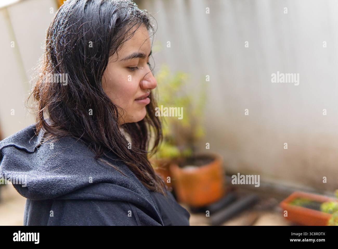 Jeune femme mouillée sous la pluie avec une expression triste sur son visage Banque D'Images