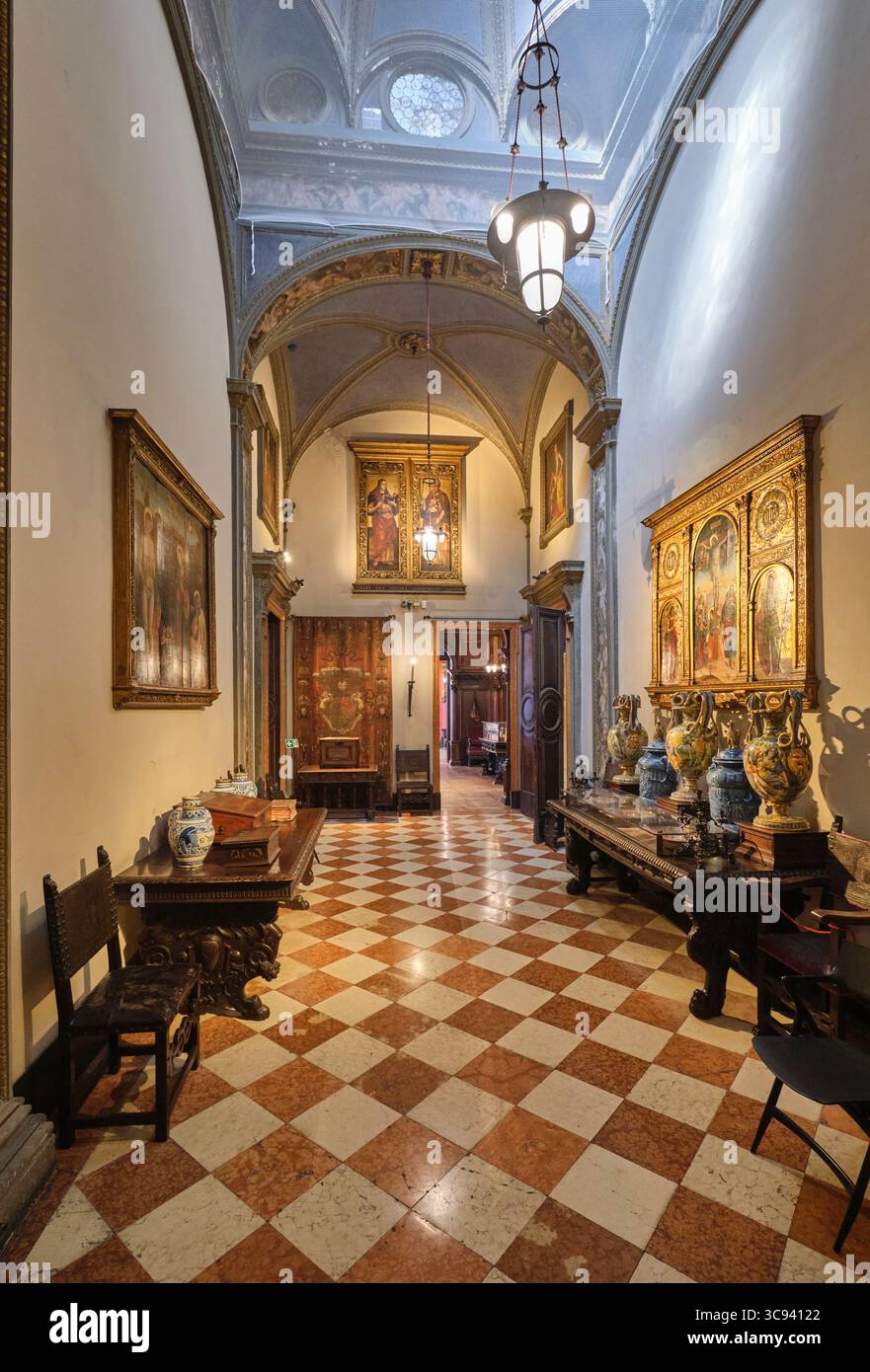Un couloir avec carreaux en damier, sol en marbre et peintures religieuses sur les murs. Au musée Bagatti Valsecchi à Milan, Italie. Banque D'Images