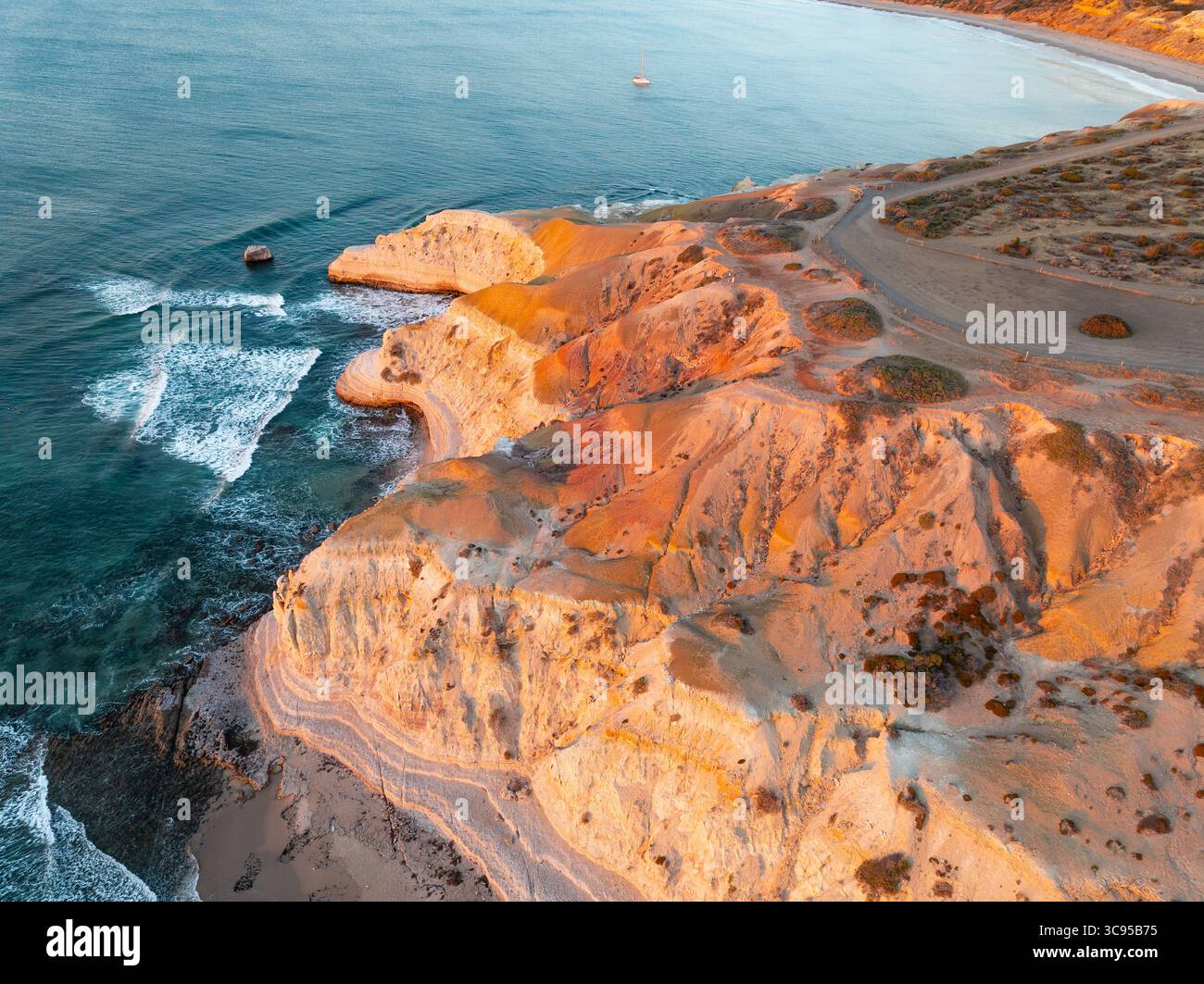 Vue aérienne d'un belvédère au-dessus de falaises côtières accidentées sous un soleil doré à Maslin Beach sur la péninsule de Fluerieu en Australie méridionale Banque D'Images
