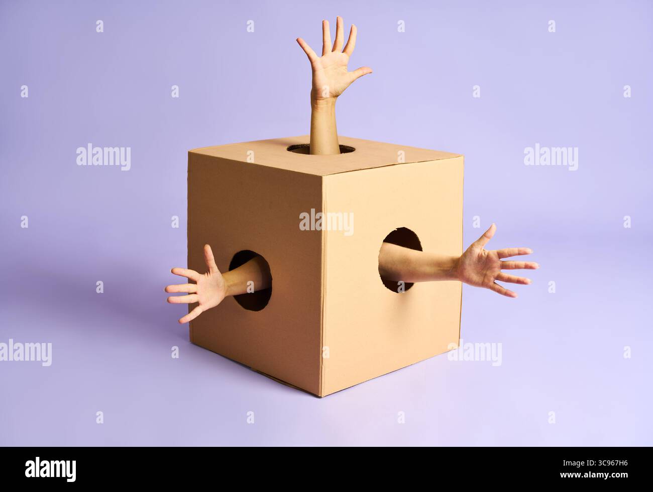 Image surréaliste de plusieurs bras humains atteignant hors des trous dans la boîte en carton sur fond bleu. Banque D'Images