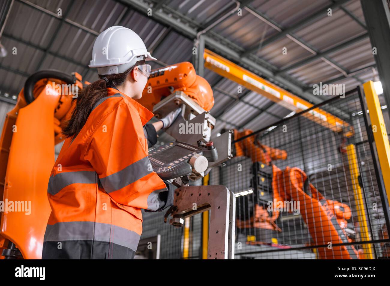 Les femmes ingénieurs techniciens testent le contrôle d'inspection de l'installation de bras de robot en usine. robot de reglage de verification de travailleur avec dispositif de commande Banque D'Images