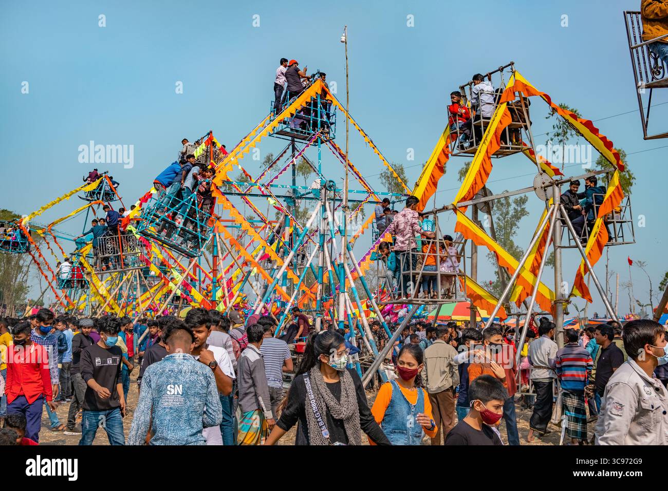 Bogura, Bangladesh - 03 novembre 2023 : vue sur le champ de foire vibrant, où les grandes roues créent une silhouette ludique dans le ciel dégagé, vivant de couleurs. Banque D'Images
