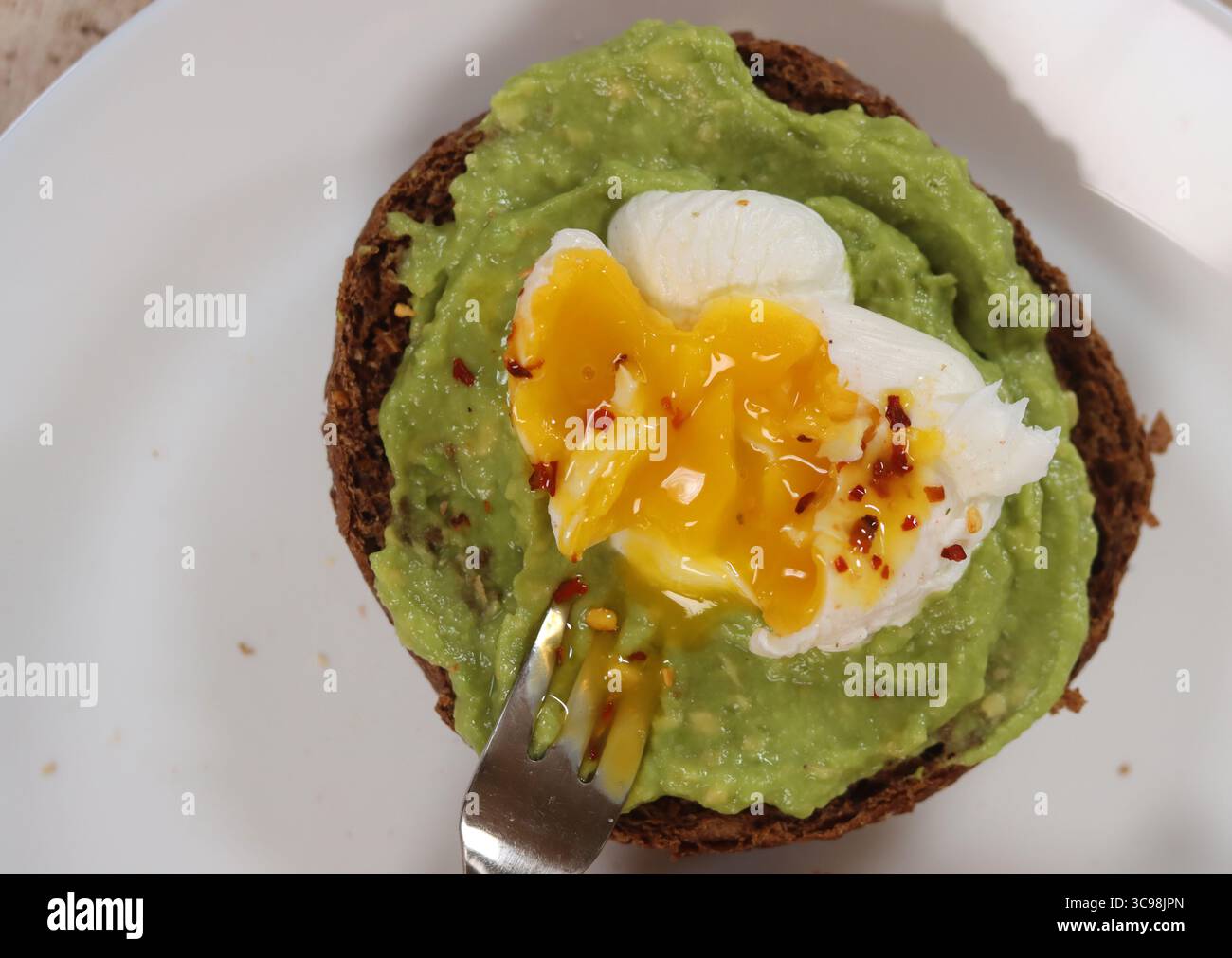 Toast à l'avocat avec oeuf poché sur une assiette blanche, gros plan Banque D'Images