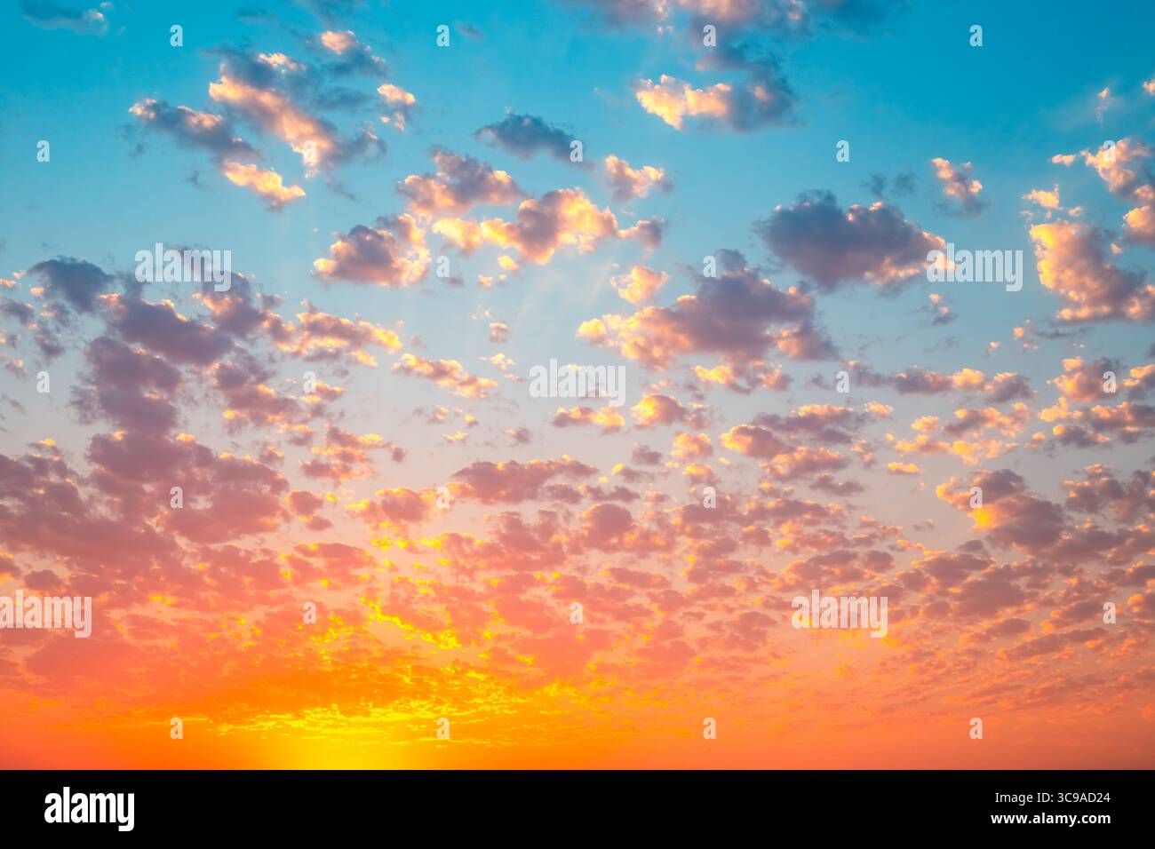 Le ciel est enflammé avec les teintes chaudes du coucher du soleil, parsemé de nuages doux avec un bord doré. Banque D'Images