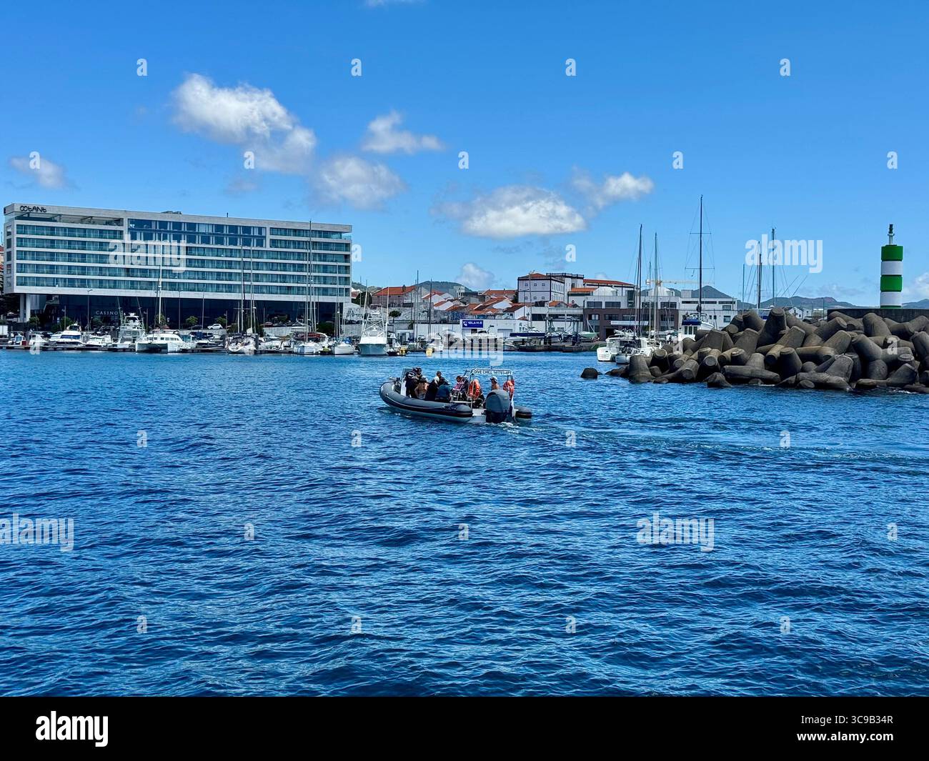 Bateau rapide touristique de retour à la marina de Ponta Delgada après un voyage de plongée, avec la montagne volcanique de Lagoa do Fogo en arrière-plan, São Miguel Isl Banque D'Images