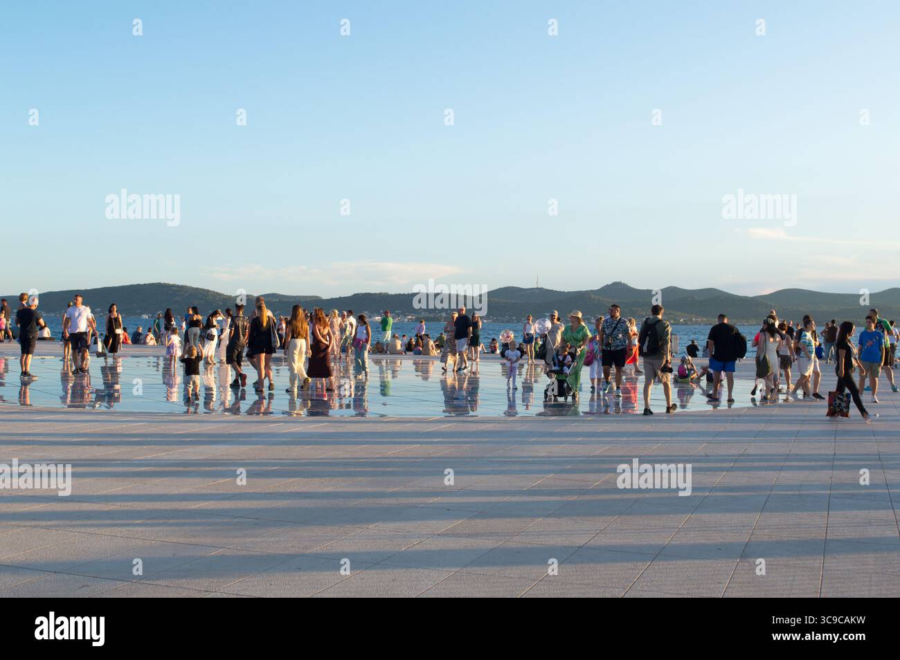 Zadar, Croatie - 27 juillet 2025 : les touristes visitent et apprécient l'attraction célèbre, salutation au soleil et l'installation d'orgue de mer, instrument de musique qui pl Banque D'Images
