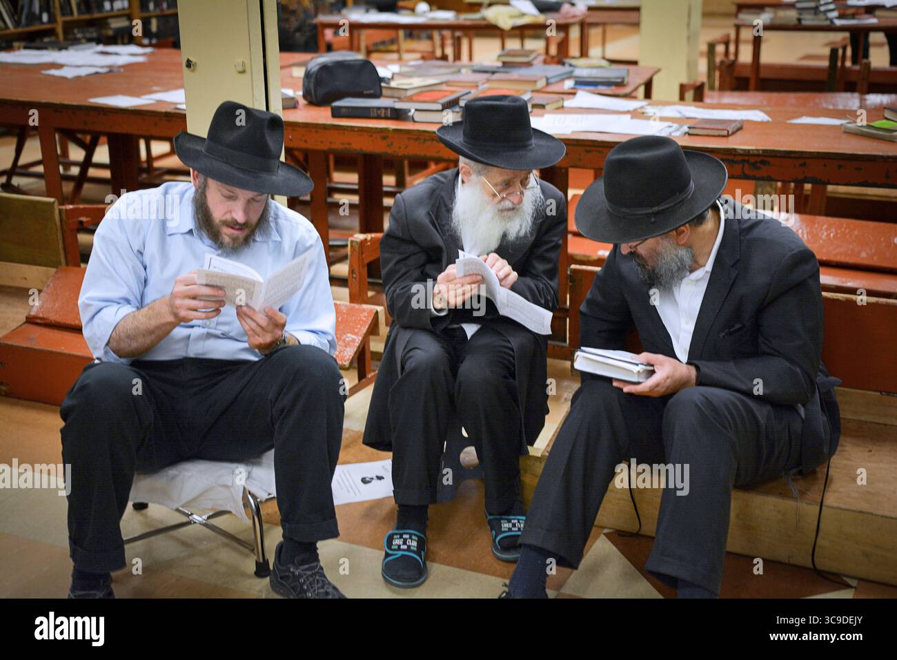 Un petit groupe d'hommes religieux juifs étudient avant les services du matin de Tisha B'AV dans une synagogue de Brooklyn, New York. Banque D'Images