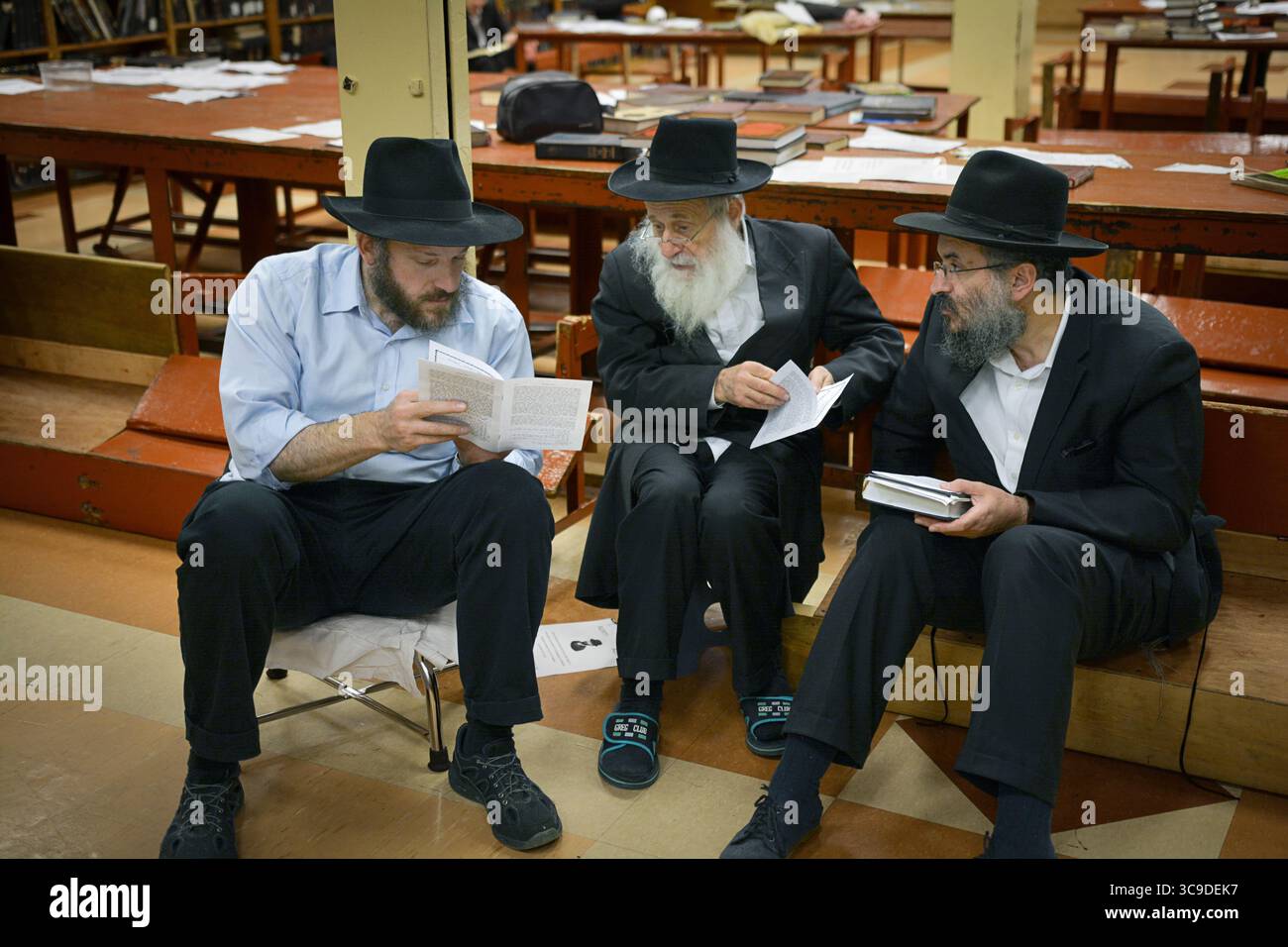 Un petit groupe d'hommes religieux juifs étudient avant les services du matin de Tisha B'AV dans une synagogue de Brooklyn, New York. Banque D'Images