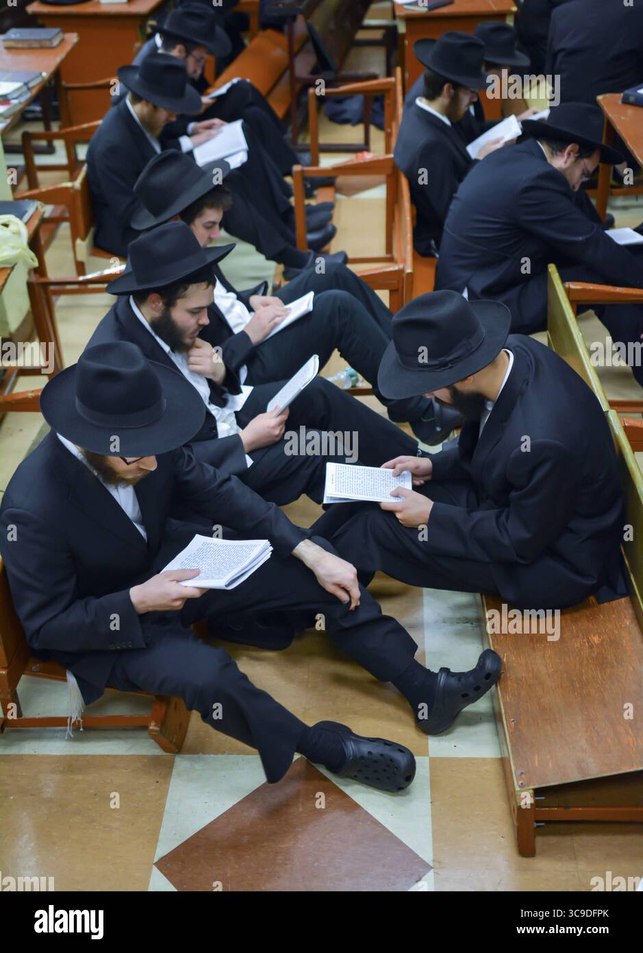Sur Tisha B'av, le jour le plus triste du calendrier juif, les fidèles pleurent assis sur des bancs renversés. Dans une synagogue à Crown Heights, Brooklyn, New York. Banque D'Images