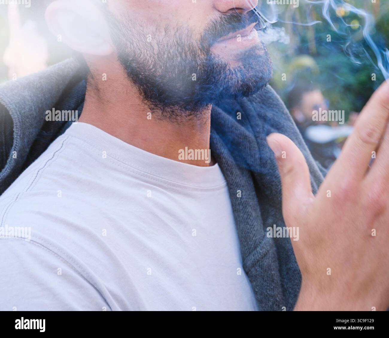 Gros plan de la partie inférieure du visage de l'homme fumeur dans le centre de la ville européenne, le visage est méconnaissable Banque D'Images