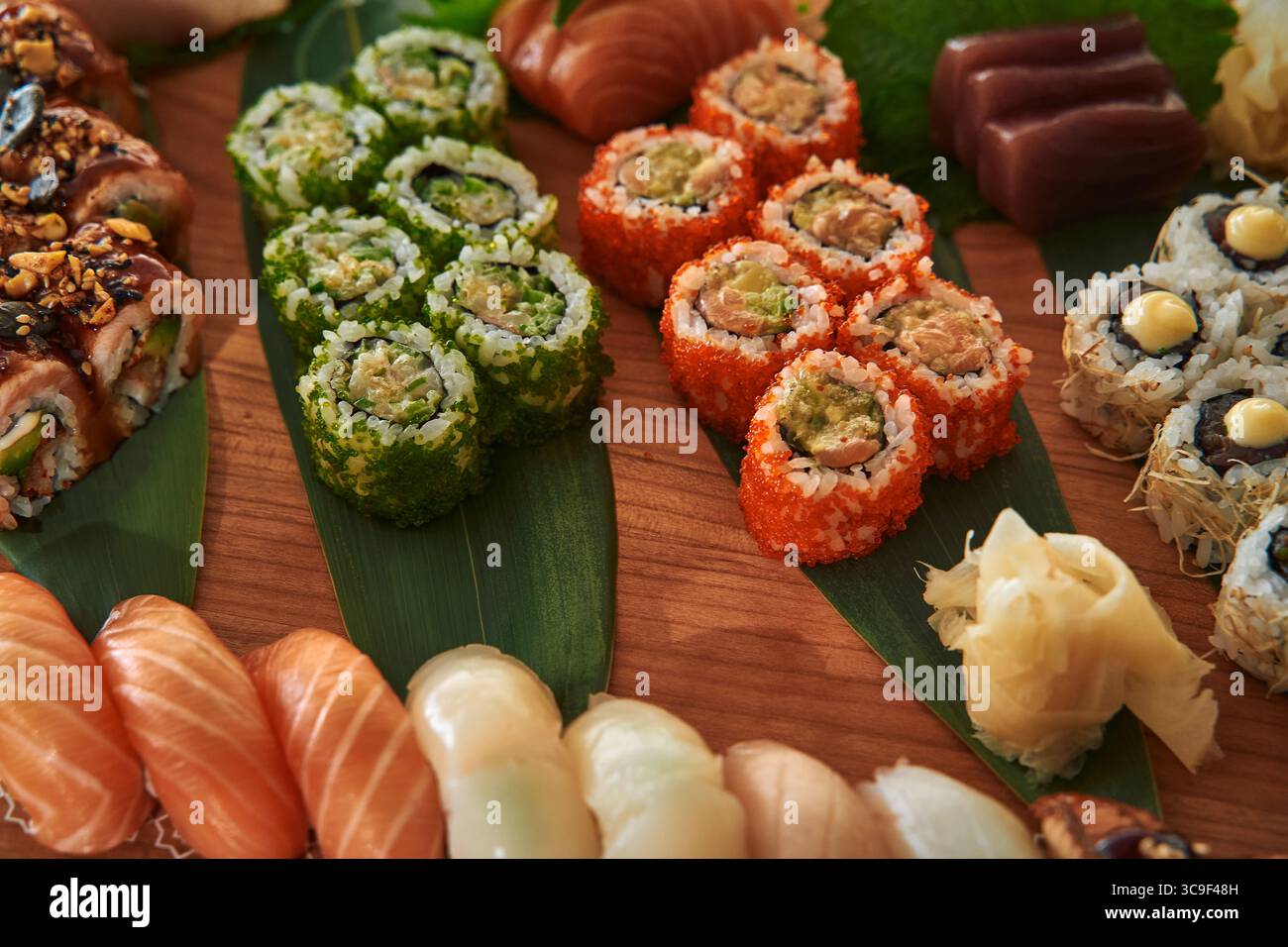 Un assortiment coloré de Sushi Rolls et de Sashimi sur un plateau en bois avec divers ingrédients et styles de présentation pour une expérience culinaire artistique Banque D'Images