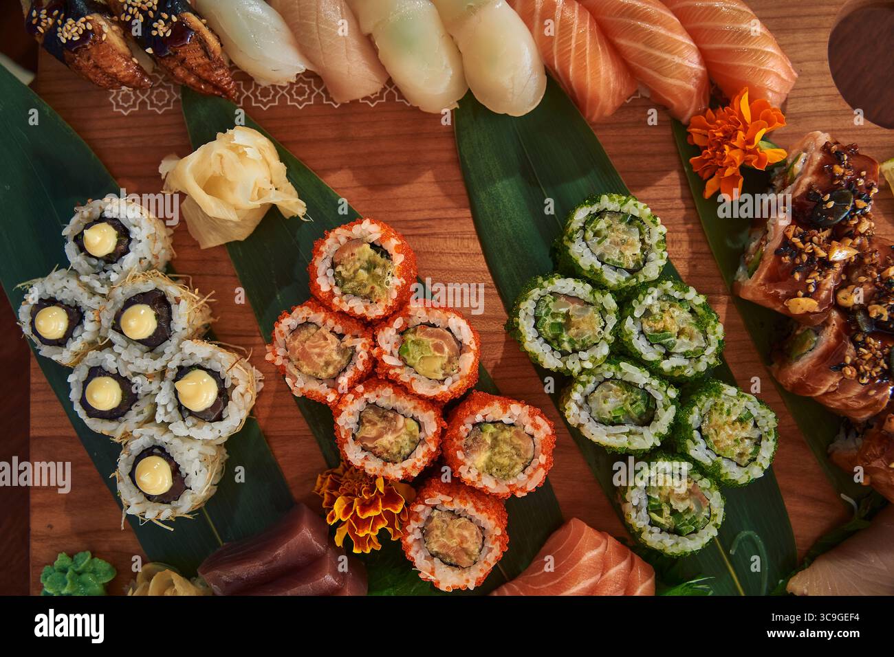 Un tableau exquis de Sushi Rolls colorés et de délices présentés avec art sur un plateau en bois garni d'ingrédients frais Banque D'Images
