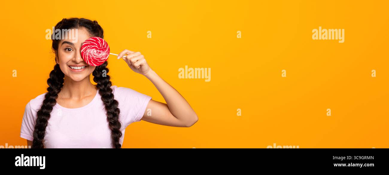 Femme indienne tenant une lollipop, couvrant l'œil avec des bonbons Banque D'Images