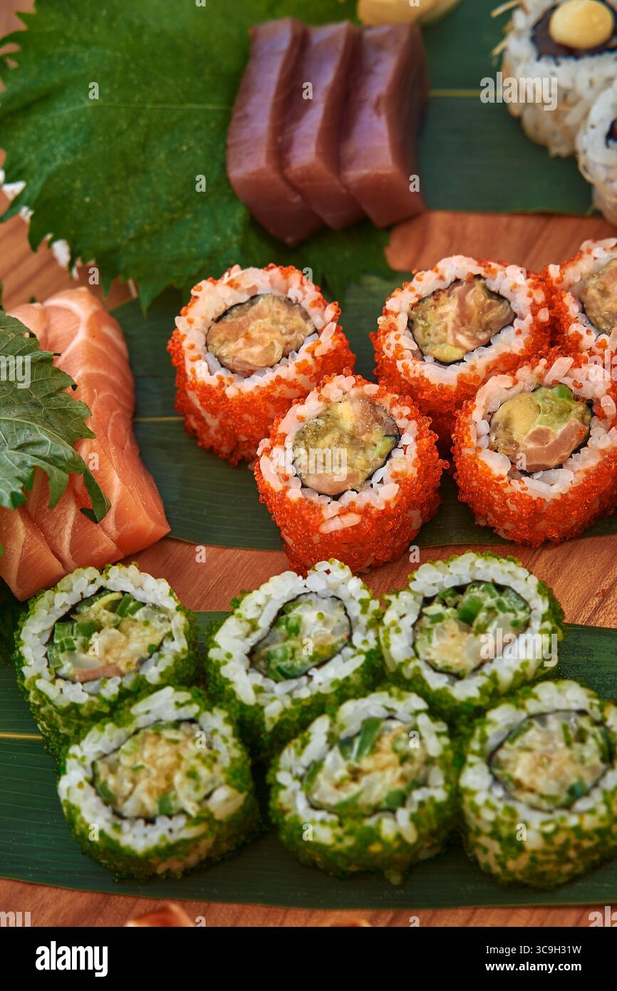 Un assortiment coloré de Sushi Rolls avec des ingrédients frais et des saveurs variées arborant habilement une planche en bois Banque D'Images