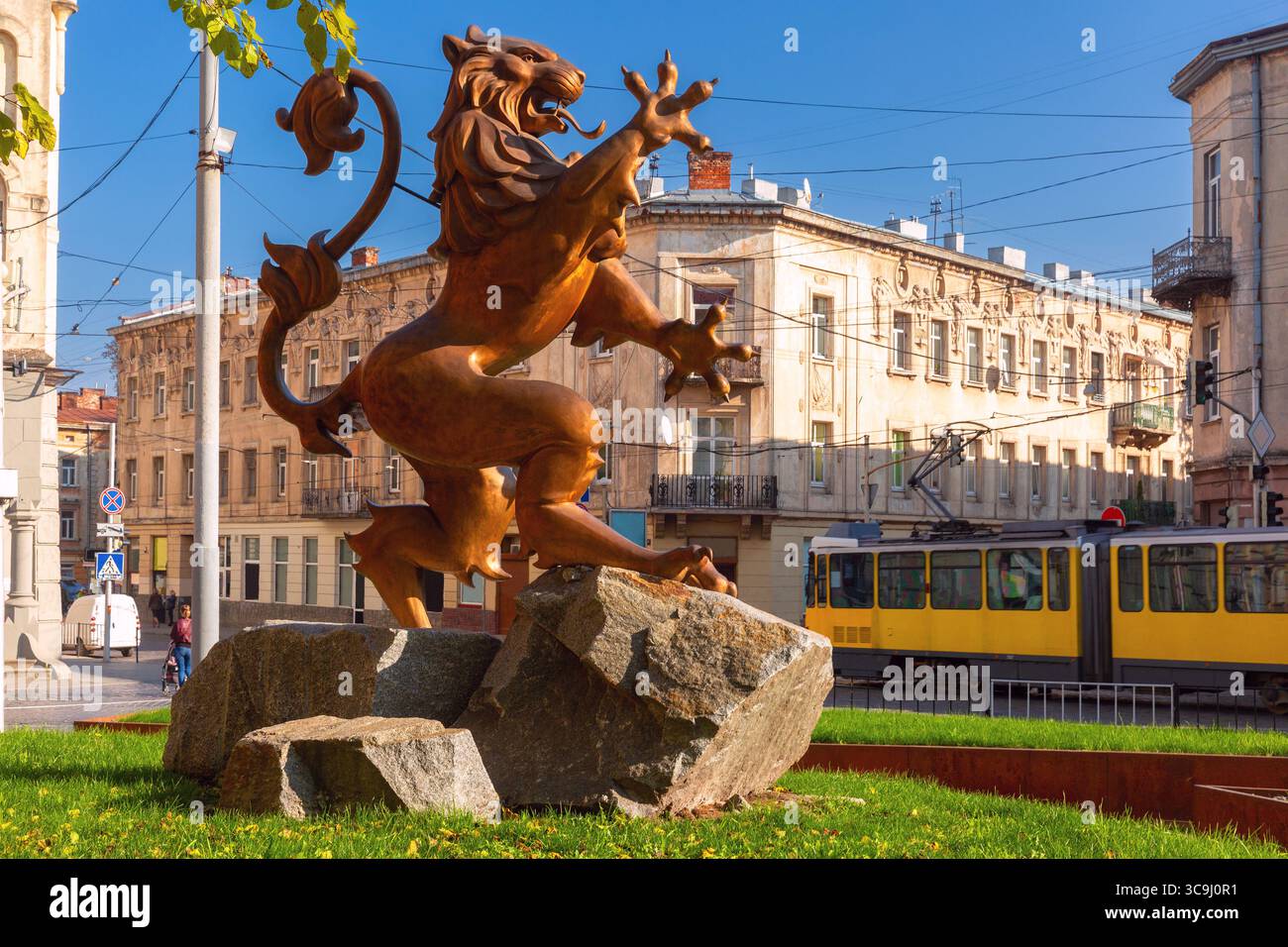 Sculpture de lion en bronze avec tramway jaune passant et vieux bâtiments à Lviv, Ukraine Banque D'Images