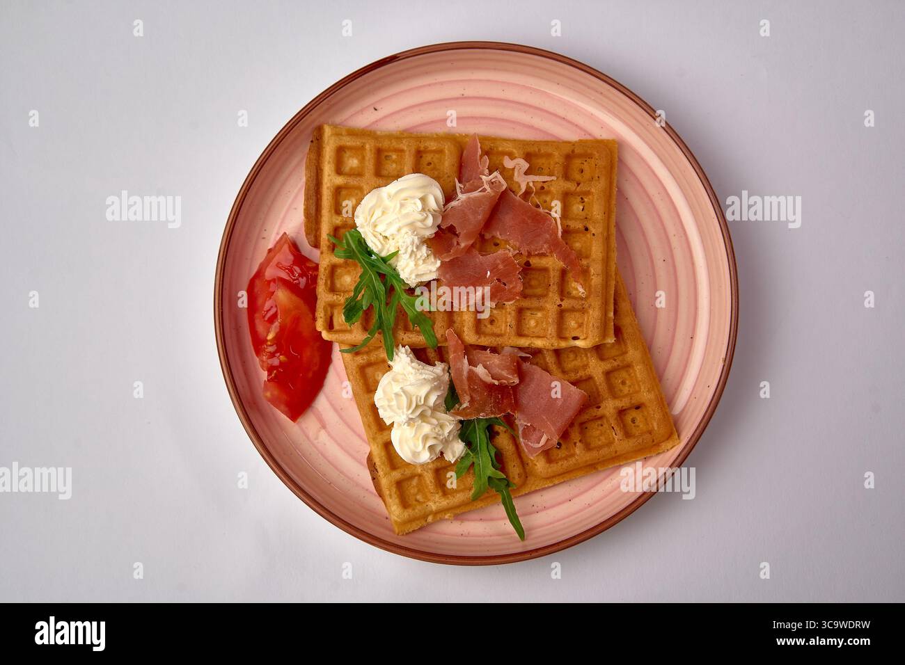 Gaufres délicieusement confectionnées avec garniture fouettée crémeuse, Arugula fraîche et Prosciutto savoureux, présentées sur une assiette élégante Banque D'Images