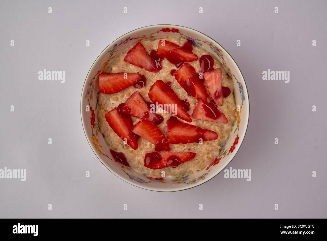 Délicieux bol de flocons d'avoine garni de fraises fraîches et d'un filet de sirop pour un petit déjeuner nutritif Banque D'Images