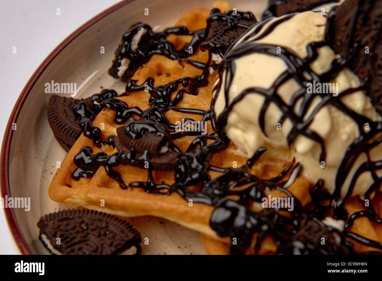 Gaufres délicieusement délicieuses, recouvertes de crème glacée crémeuse et assaisonnées de sauce au chocolat, agrémentées de biscuits émiettés pour une préparation parfaite Banque D'Images