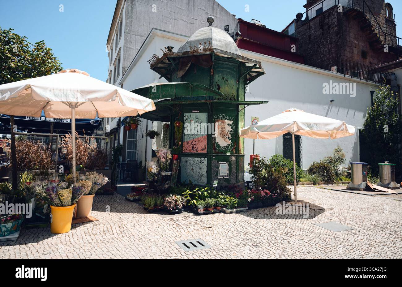 Charmant kiosque de fleurs à Braga entouré de plantes, de parasols de rue et de pavés par une journée d'été lumineuse Banque D'Images