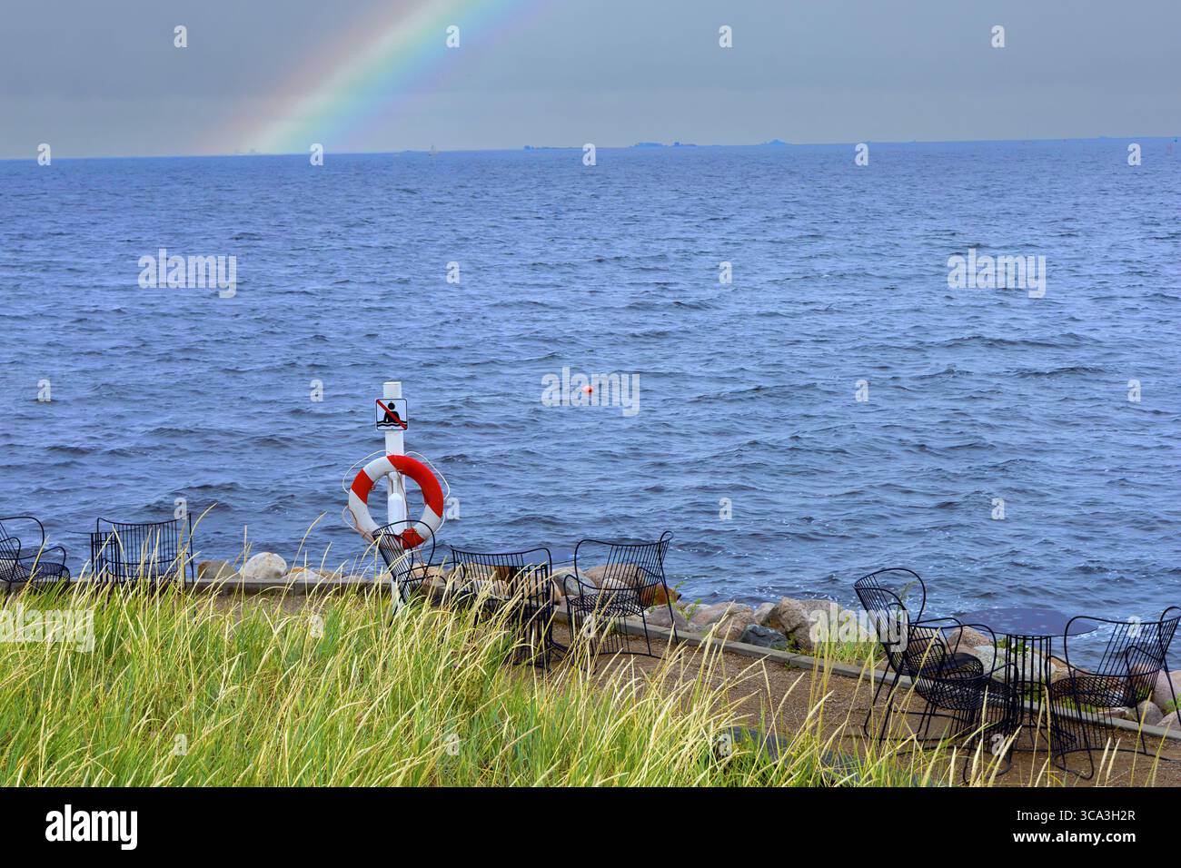 Bouée de sauvetage au bord de la mer avec un arc-en-ciel dans le ciel. Photo de haute qualité Banque D'Images