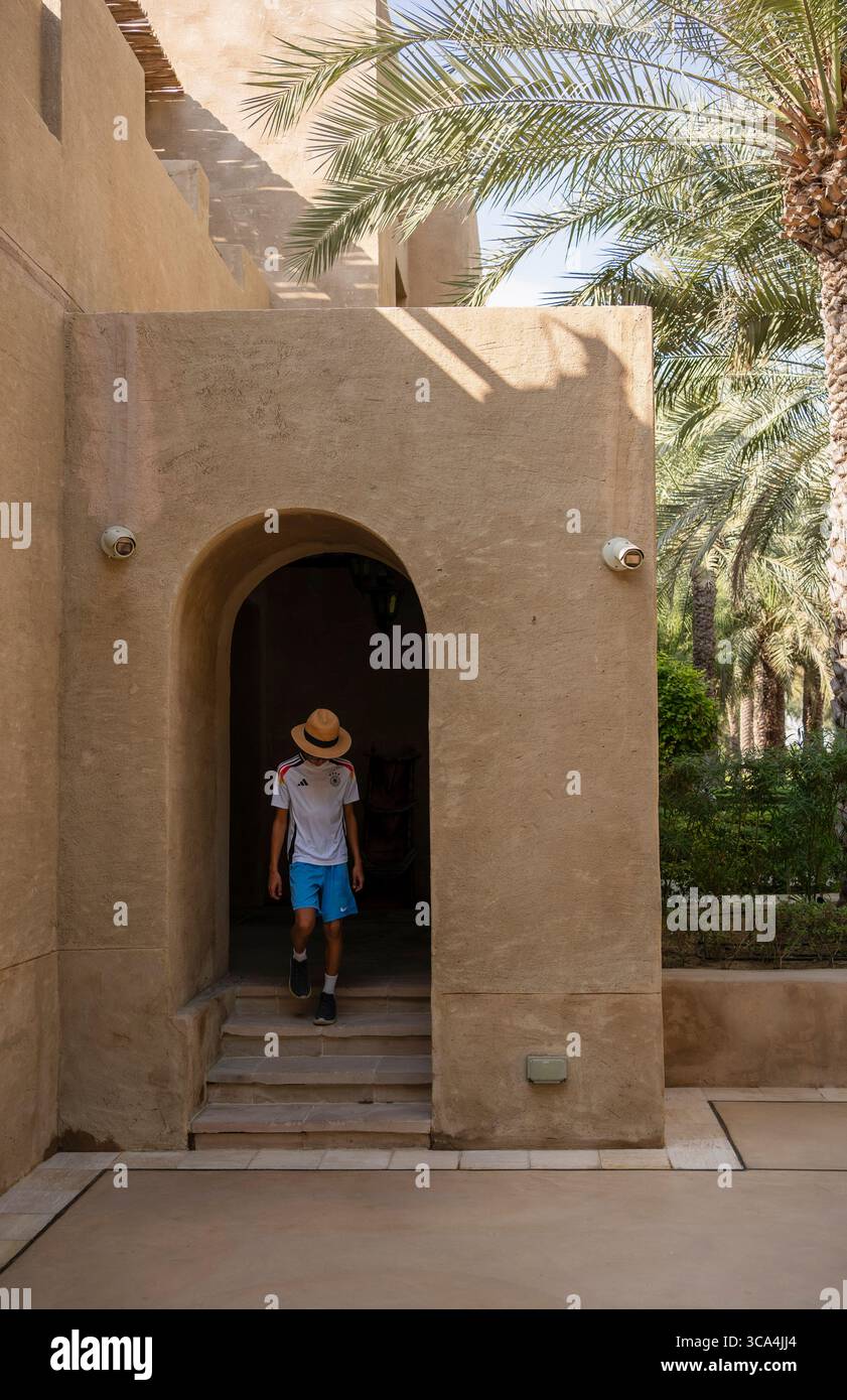 Garçon touriste entrant dans un bâtiment traditionnel à Bab Al Shams Resort, Dubaï, Émirats arabes Unis Banque D'Images