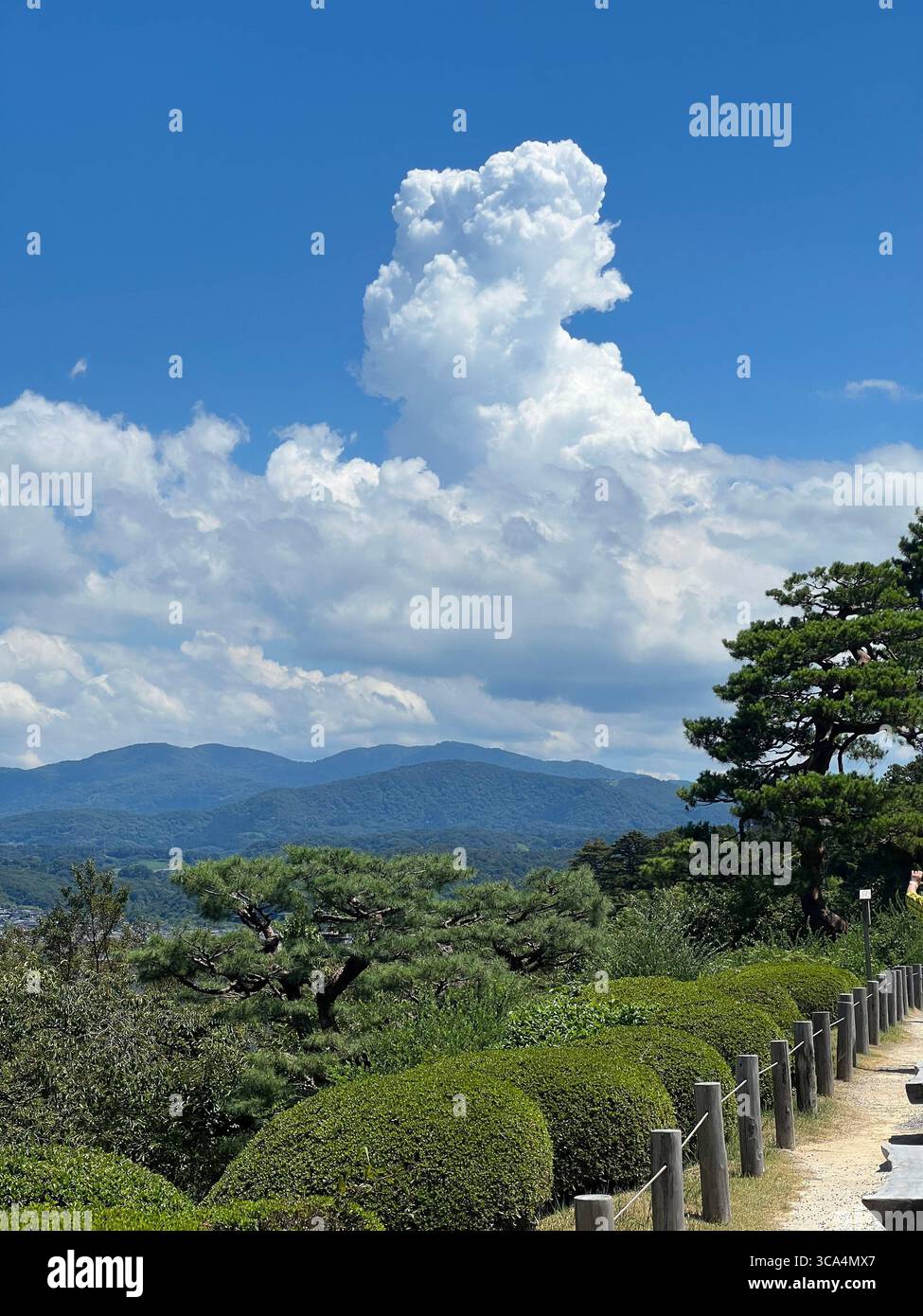 Des nuages majestueux s’élèvent sur la verdure luxuriante de Kenrokuen, encadrant un chemin serein avec vue sur la montagne à Kanazawa, au Japon. Banque D'Images