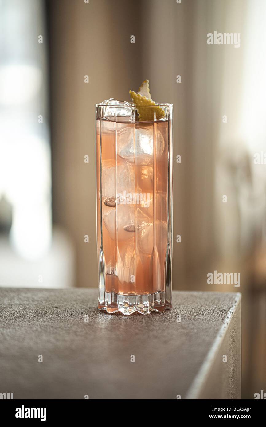 Cocktail rose dans un grand verre avec citron et glace Banque D'Images
