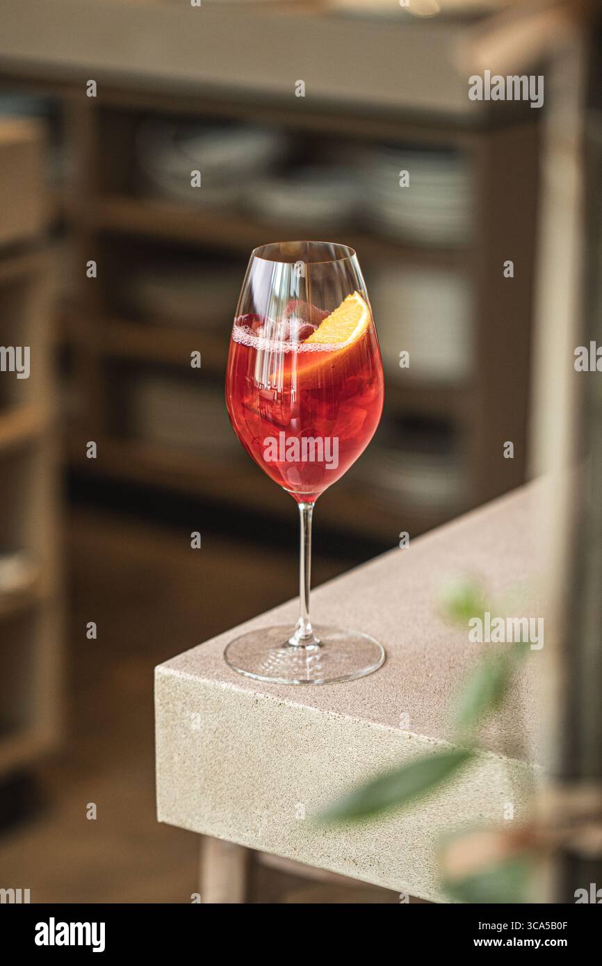 Cocktail rouge avec orange et glace dans un verre à vin Banque D'Images