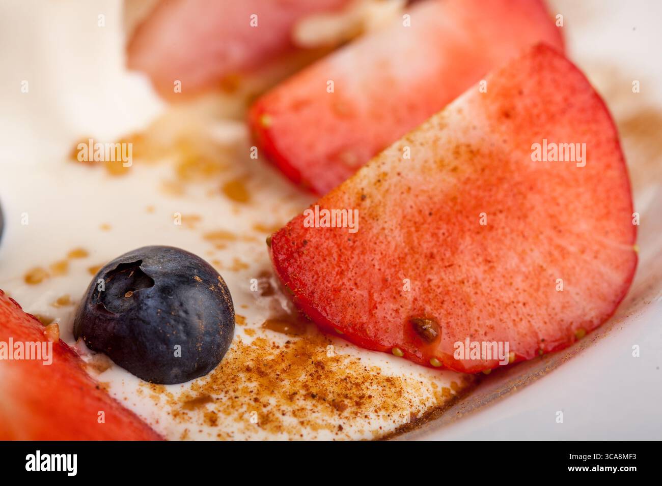 Un gros plan de tranches de fraises fraîches aux épices et aux myrtilles, qui font partie d'un délicieux dessert glacé, un régal sain et rafraîchissant Banque D'Images