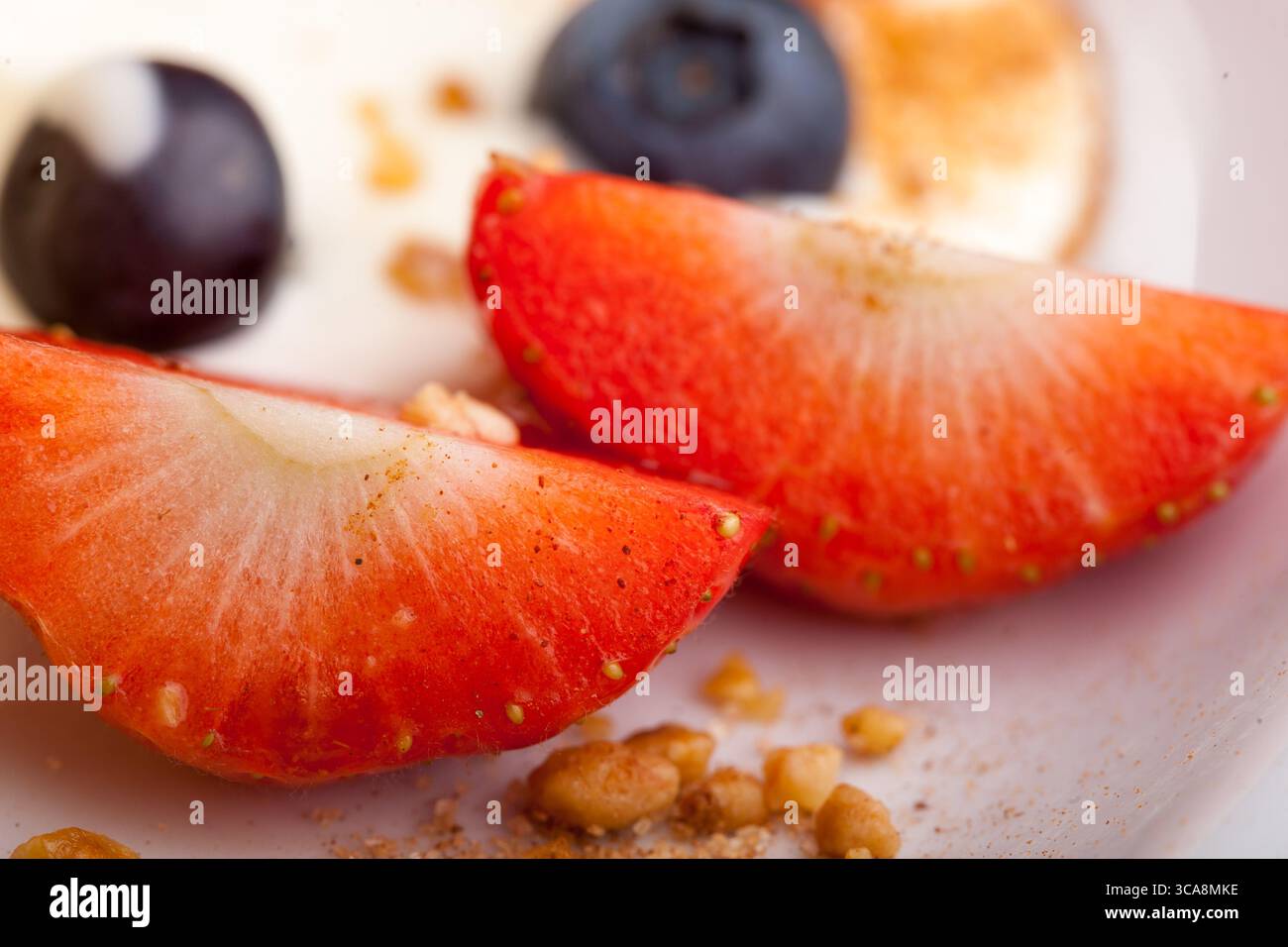 Un gros plan de tranches de fraises fraîches aux épices et aux myrtilles, qui font partie d'un délicieux dessert glacé, un régal sain et rafraîchissant Banque D'Images