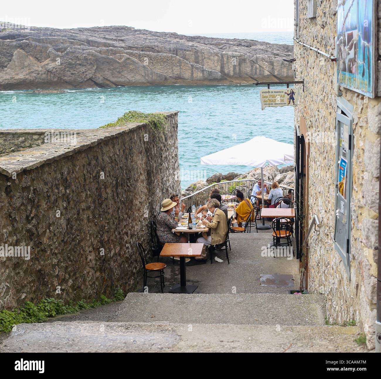Llanes, Espagne, 6 août 2025 : plusieurs personnes mangent avec la mer Cantabrique en arrière-plan pendant la vie quotidienne à Llanes, le 6 août 2025, à Llanes, Espagne. Crédit : Alberto Brevers / Alamy Live News. Banque D'Images