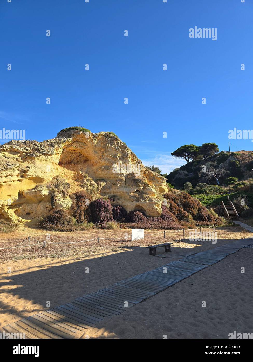 Départ du sentier de randonnée côtier à Albufeira, Algarve, Portugal, avec des falaises rocheuses et un ciel bleu clair par une journée ensoleillée. - Image de stock capturée avec un smartphone