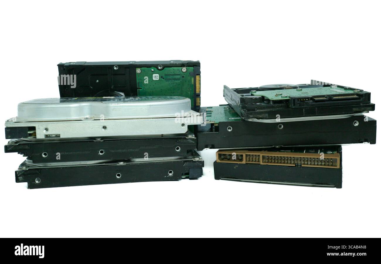 Pile de grands disques durs obsolètes avec de vieux connecteurs, disposés sur fond blanc de studio, symbolisant les déchets électroniques et la technologie obsolète. Banque D'Images