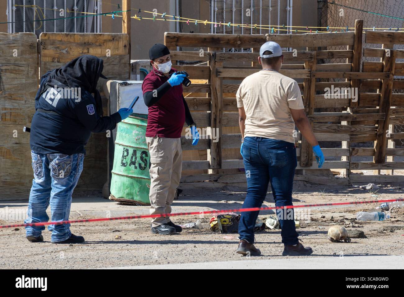 Un officier de Balaclava examine des documents au milieu de civils à Ciudad Juarez, un point chaud de la violence urbaine. Banque D'Images